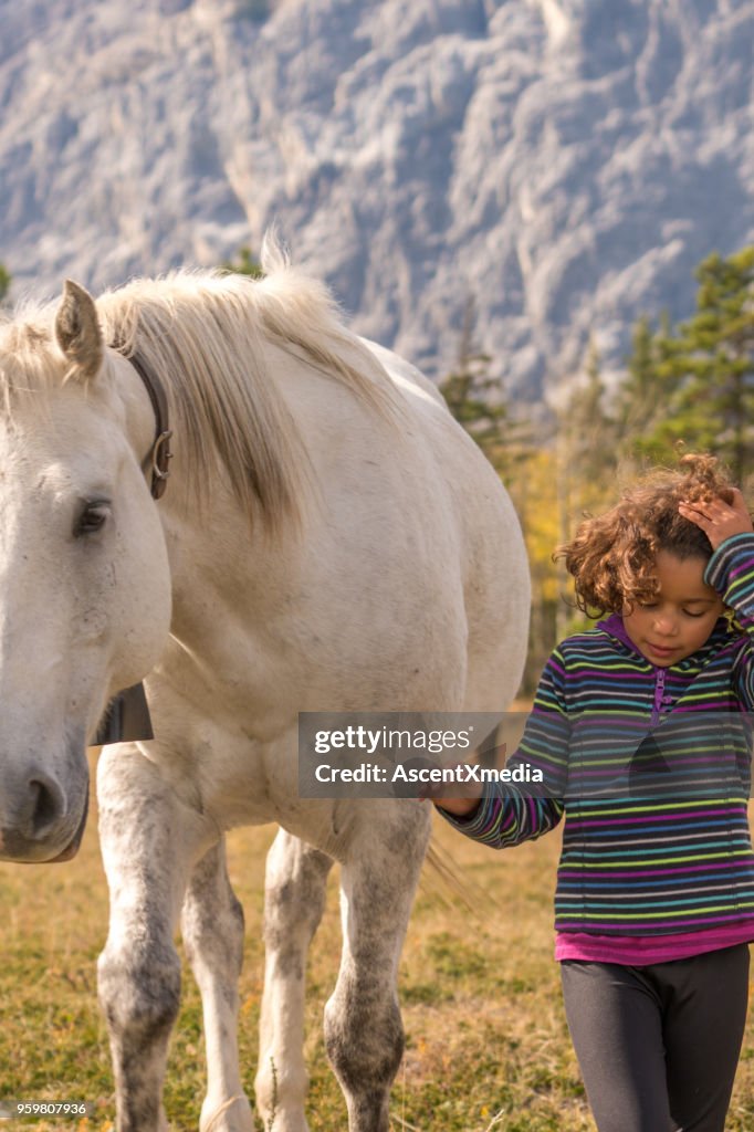 Mixed race girl connects with horses below mountains