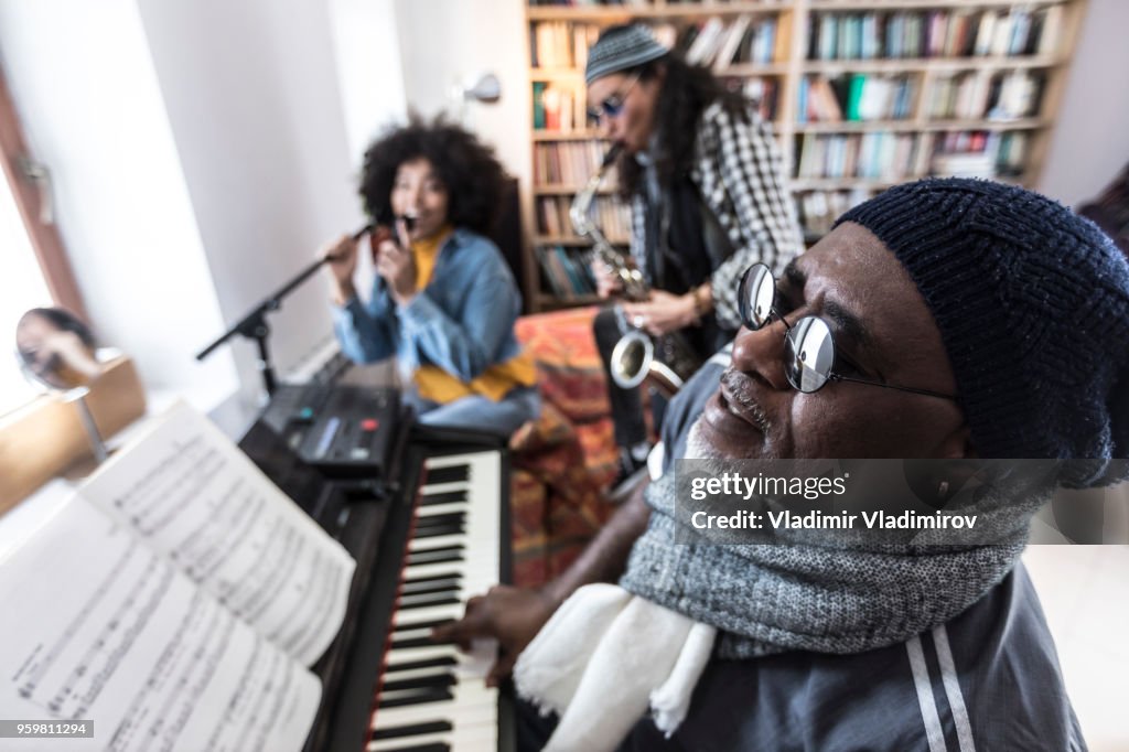 Mature african man playing the piano with friends