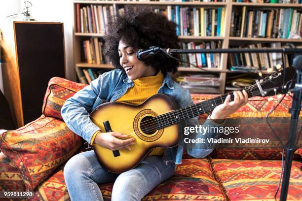 heureuse femme africaine chanter et jouer de la guitare en studio - auteur de chansons photos et images de collection