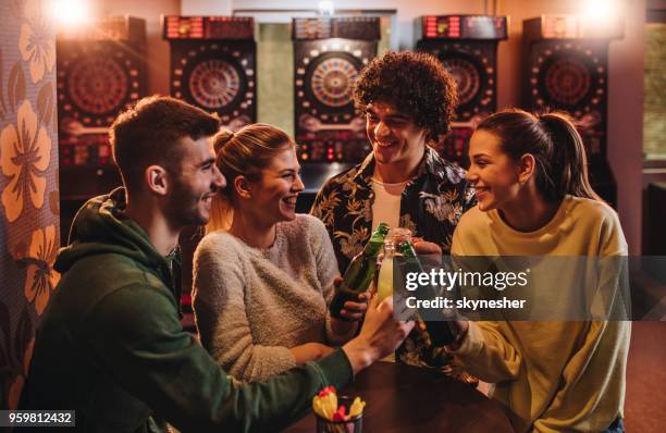 young cheerful friends toasting after playing darts in a bar. - pub darts stock pictures, royalty-free photos & images