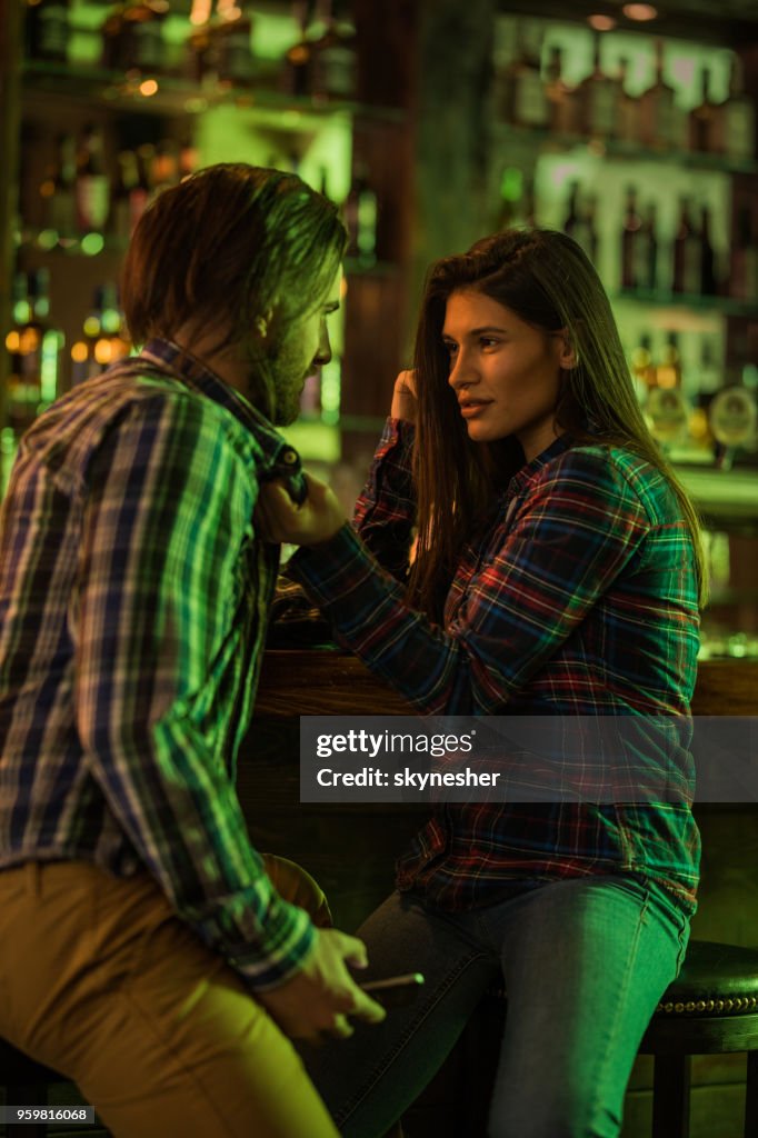 一對年輕情侶在酒吧裡互相交談。