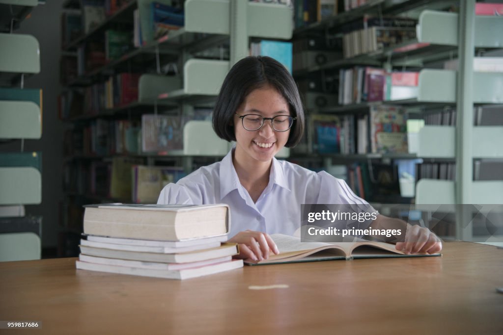 Asian student girl reading book in public library