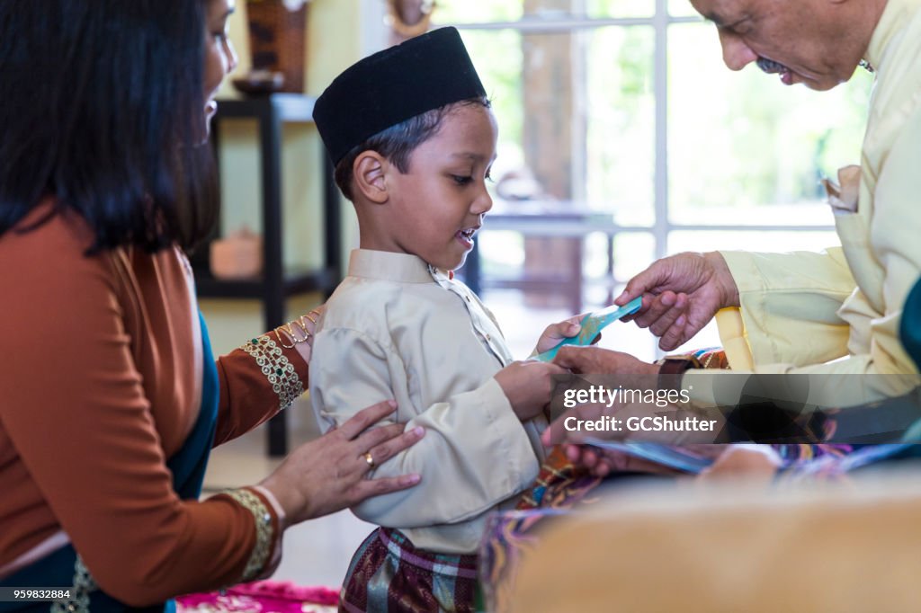 Grandson receiving gift from grandfather during Eid