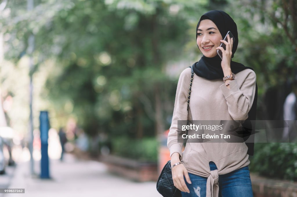 有魅力的馬來女士與頭巾在電話溝通