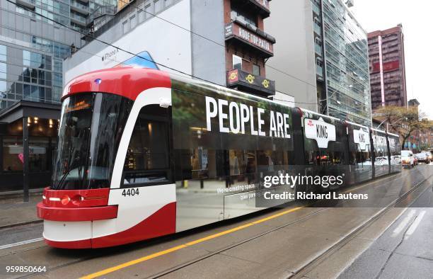 New streetcar with banners advertising the change drives by the crew setting up the new signs. A crew from Guild Electric is seen setting up the new...