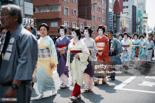 Women in traditional geisha dress parade down the street toward Asakusa Shrine during Tokyo's one of the largest three day festival called...