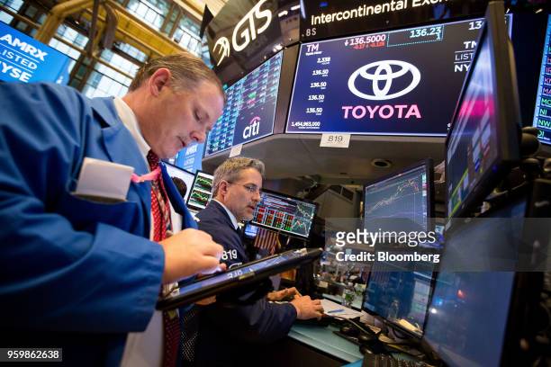 Traders work beneath a monitor displaying Toyota Motor Corp. Signage on the floor of the New York Stock Exchange in New York, U.S., on Friday, May...