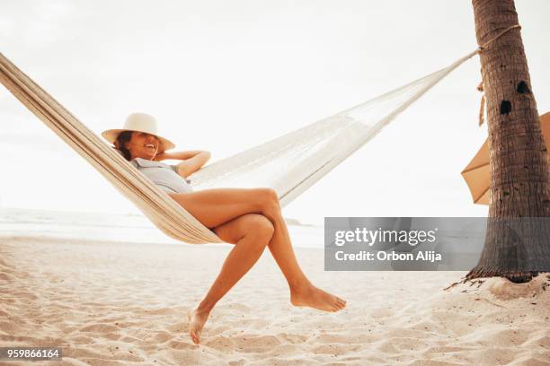 vrouw ontspannen in een hangmat op strand - legs stockfoto's en -beelden