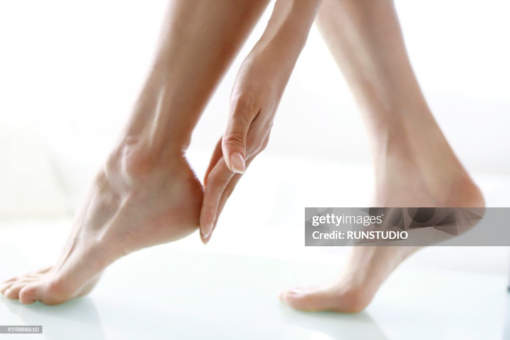 Woman touching feet, low section, close-up