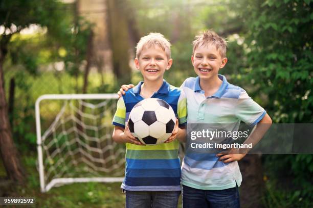 zwillingsbrüder fußball im garten genießen - twins boys stock-fotos und bilder