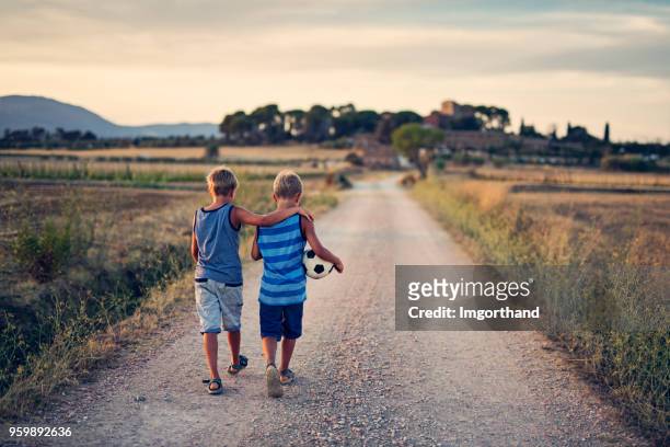 twin brothers returning home after playing soccer. - brother hug stock pictures, royalty-free photos & images