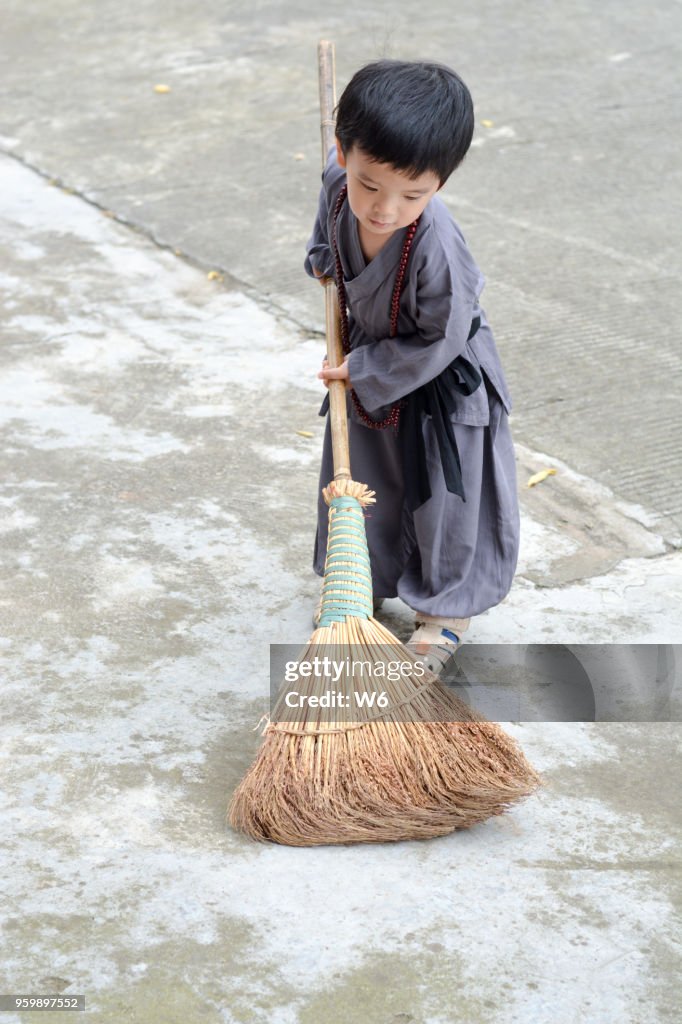 Little happy apprentice is sweeping the floor