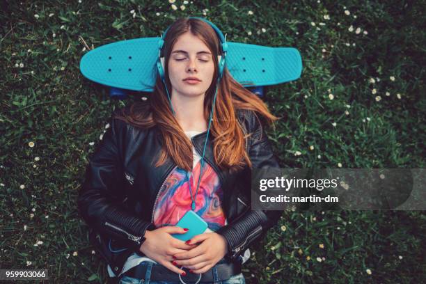relaxed teenage girl in the grass listening to music - flop stock pictures, royalty-free photos & images