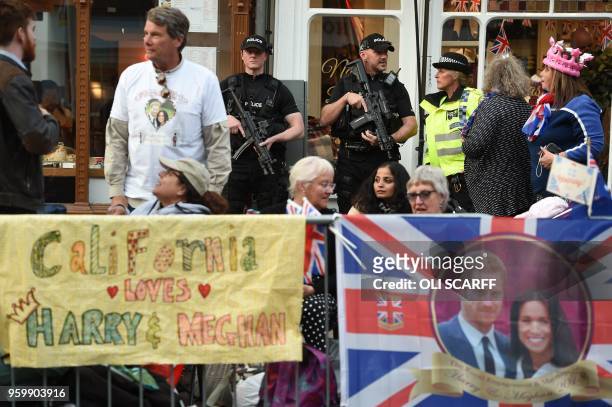Armed police stand guard as Royal well-wishers prepare to bed down for the night on the High Street outside Windor Castle in Windsor on May 18 the...