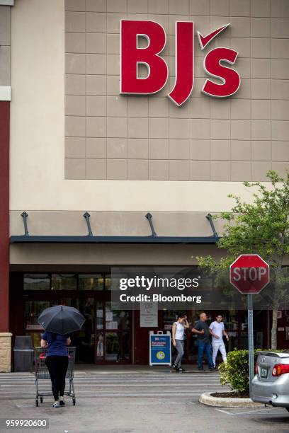Customer holds an umbrella while walking towards the entrance of a BJ's Wholesale Club Holdings Inc. Location in Miami, Florida, U.S., on Thursday,...