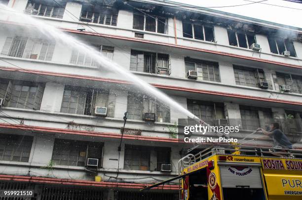 Onlookers watch firemen put out fire that broke out at Wellington Building in Binondo, Manila, Philippines, on 18 May 2018. A fire of still unknown...