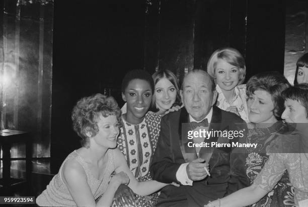 English actor and playwright Noel Coward pictured with members of the cast at the premiere of his musical revue 'Cowardy Custard' at the Mermaid...