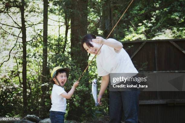 mother and son fishing a trout in the mountain together - cana de pesca imagens e fotografias de stock