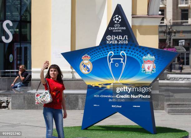 An Ukrainian woman takes a selfie near a large sign showcasing the logo for the 2018 UEFA Champions League Final in central Kiev, Ukraine, 18 May,...