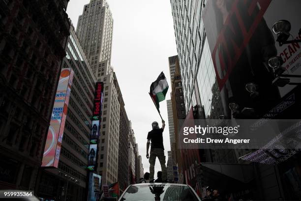 Protestor waves a Palestinian flag while standing atop a truck during rally in support of the Palestinian people in the wake of the recent violence...