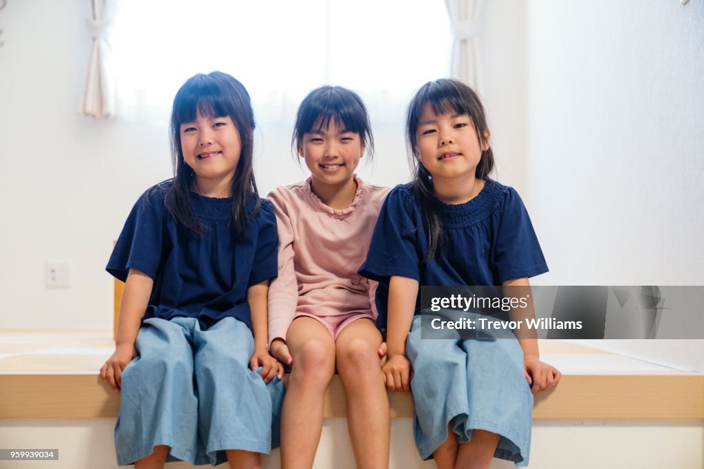 Twin girls sitting together with older sister