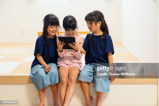 twin girls looking at a digital tablet with older sister - digital twin bildbanksfoton och bilder