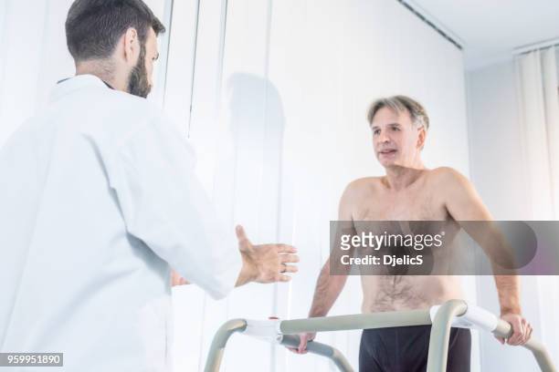 doctor helping mature patient walk after operation. - doctor's surgery stock pictures, royalty-free photos & images