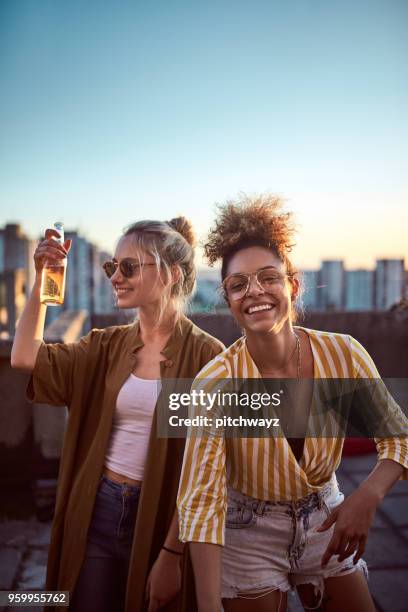 two women cheering at roof party. - rooftop party stock pictures, royalty-free photos & images