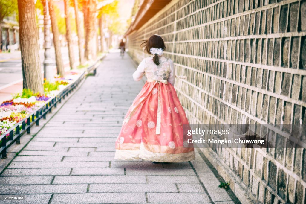 Young asian woman traveler in korean national dress or Hanbok walking traveling into the Gyeongbokgung Palace at Seoul city, South Korea.