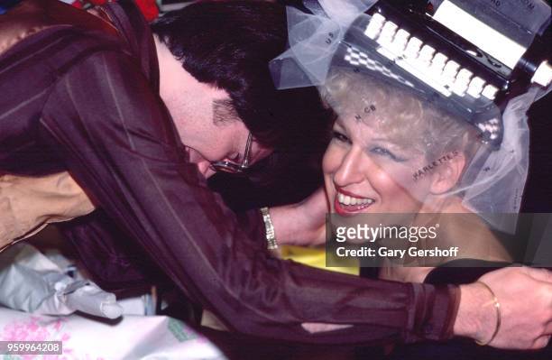 American singer, actress, and author Bette Midler smiles as an unidentified man hugs her during a book signing at a B Dalton bookseller, New York,...