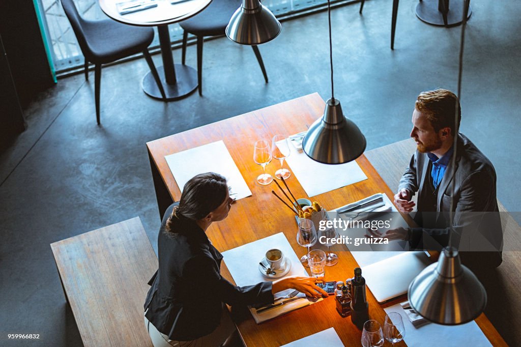 Alta vista do ângulo de um homem e uma mulher ter um conversa durante a hora do almoço em um café / restaurante