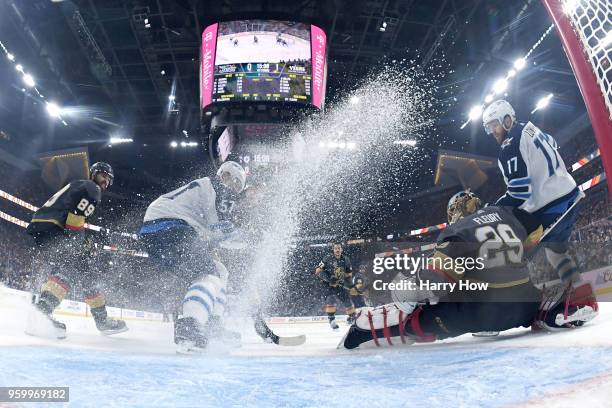 Marc-Andre Fleury of the Vegas Golden Knights makes a save against Tyler Myers and Adam Lowry of the Winnipeg Jets during the first period in Game...