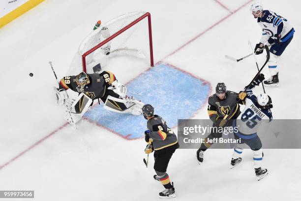 Marc-Andre Fleury makes a save while his teammates Deryk Engelland and Shea Theodore of the Vegas Golden Knights defend against Mathieu Perreault and...