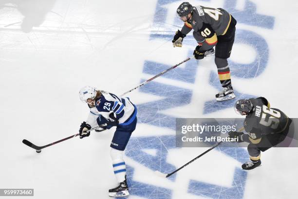 Patrik Laine of the Winnipeg Jets skates with the puck while Ryan Carpenter and Erik Haula of the Vegas Golden Knights defend in Game Four of the...