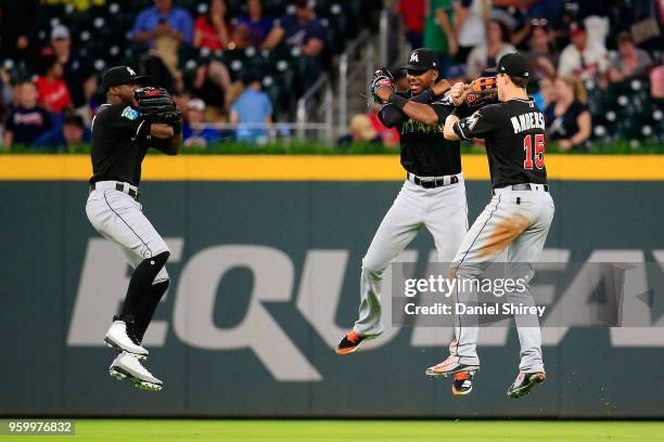 Cameron Maybin, Lewis Brinson and Brian Anderson of the Miami Marlins celebrate beating the Atlanta Braves at SunTrust Park on May 18, 2018 in...