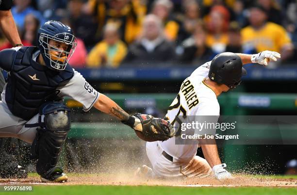 Adam Frazier of the Pittsburgh Pirates scores past Raffy Lopez of the San Diego Padres during the third inning at PNC Park on May 18, 2018 in...