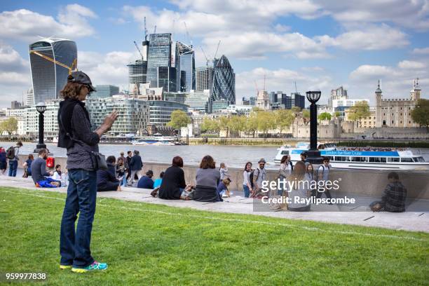 weibliche touristen fotografieren die skyline von london in der londoner riverside gegend in der nähe von potters fields park mit der berühmten walkie-talkie, aufbauend auf den horizont - potters fields park stock-fotos und bilder