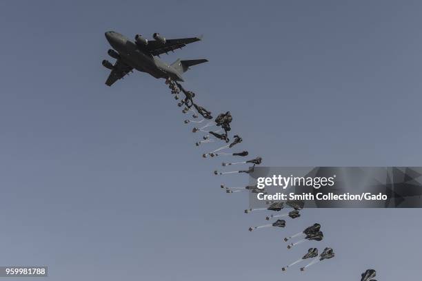 Photograph of a Qatar Emiri Air Force C-17 Globemaster military transport aircraft in flight and performing an airdrop following training by the US...