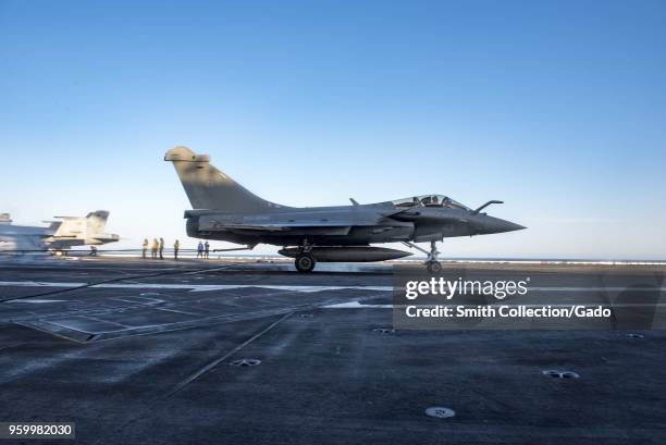 Photograph of a Rafale Marine fighter aircraft operated by the French navy landing aboard the aircraft carrier USS George HW Bush during joint...