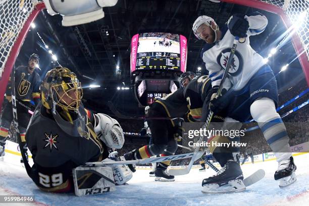 Marc-Andre Fleury of the Vegas Golden Knights and Bryan Little of the Winnipeg Jets look to the back of the net for the puck after Tyler Myers scored...