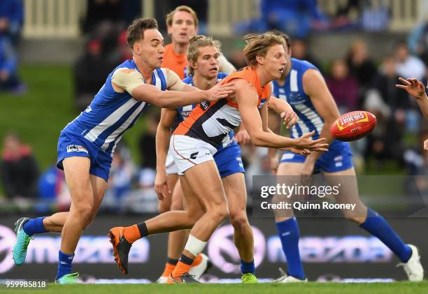 Lachie Whitfield of the Giants handballs whilst being tackled by Ryan Clarke of the Kangaroos during the round nine AFL match between the North...