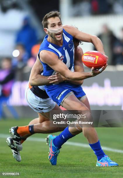 Jamie Macmillan of the Kangaroos handballs whilst being tackled during the round nine AFL match between the North Melbourne Kangaroos and the Greater...