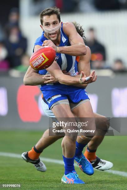 Jamie Macmillan of the Kangaroos handballs whilst being tackled during the round nine AFL match between the North Melbourne Kangaroos and the Greater...