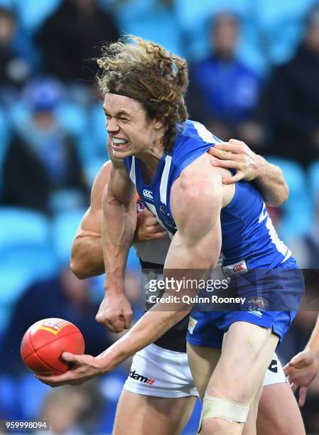 Ben Brown of the Kangaroos handballs whilst being tackled during the round nine AFL match between the North Melbourne Kangaroos and the Greater...