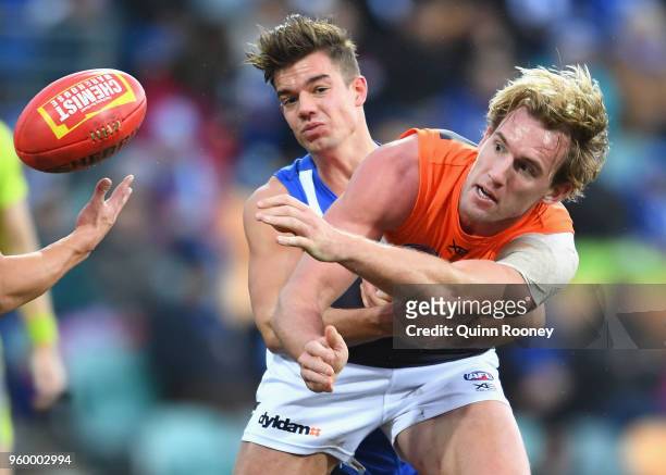 Lachlan Keeffe of the Giants handballs whilst being tackled by Jy Simpkin of the Kangaroos during the round nine AFL match between the North...