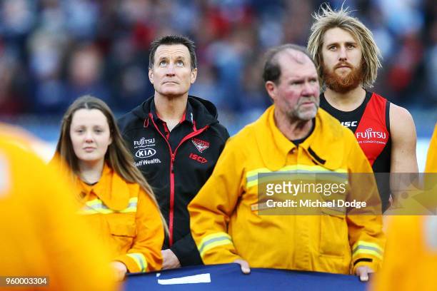 Bombers head coach John Worsfold looks up while standing in line during the ANZAC observance during the round nine AFL match between the Essendon...