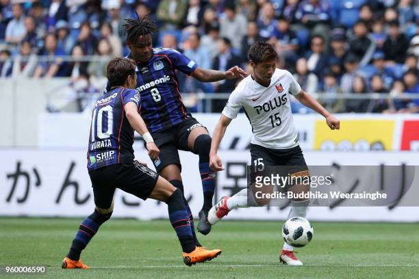 Kazuki Nagasawa of Urawa Red Diamonds controls the ball under pressure of Matheus and Shu Kurata of Gamba Osaka during the J.League J1 match between...