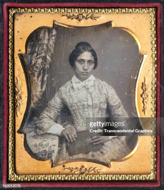 Framed daguerreotype portrait of an unidentified women as she poses with a book in her hands, circa 1850. The original caption identifies her only as...