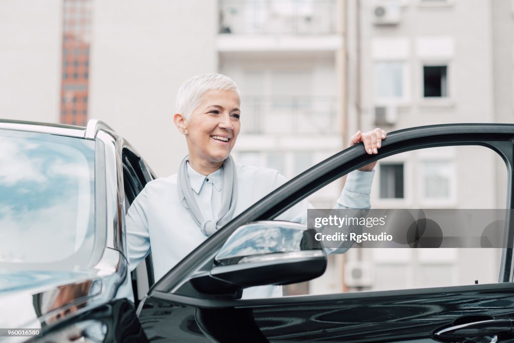 Ältere Frau Lächeln beim Betreten eines Autos