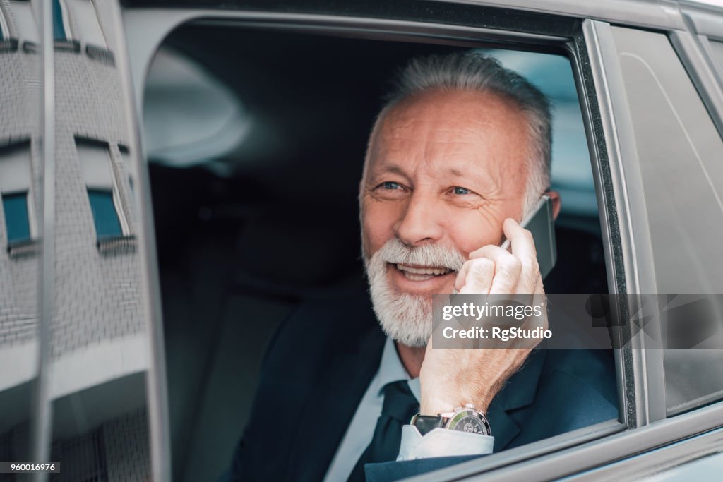 Leitenden Geschäftsmann mit Telefon in Business-Fahrzeug